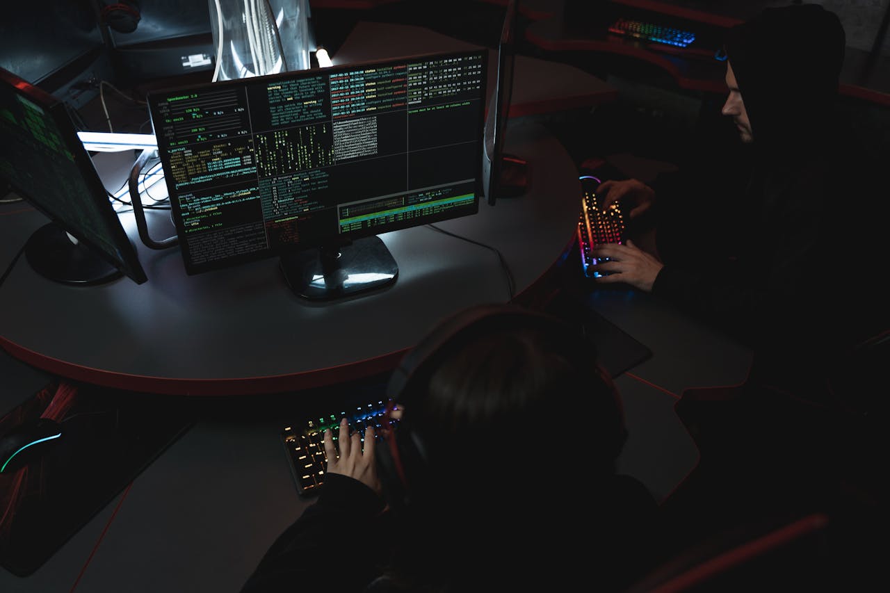 A group of people in a dark room working on computers, related to cybersecurity.